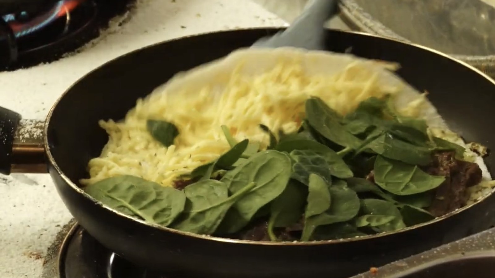 Melted cheese and fresh spinach on a tapioca base in the pan